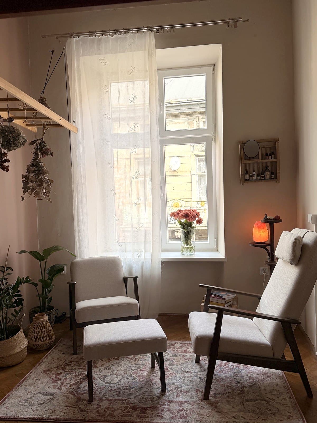 The therapy room: two armchairs by a tall window, a salt lamp and dried flowers