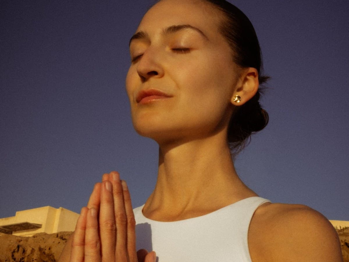 A woman with hands at her heart in the evening light