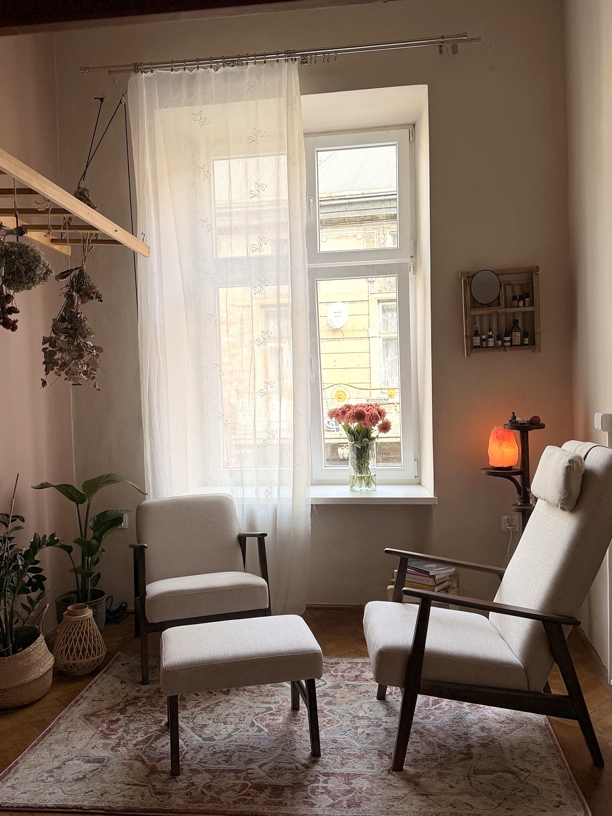 The therapy room: two armchairs by a tall window, a salt lamp and dried flowers